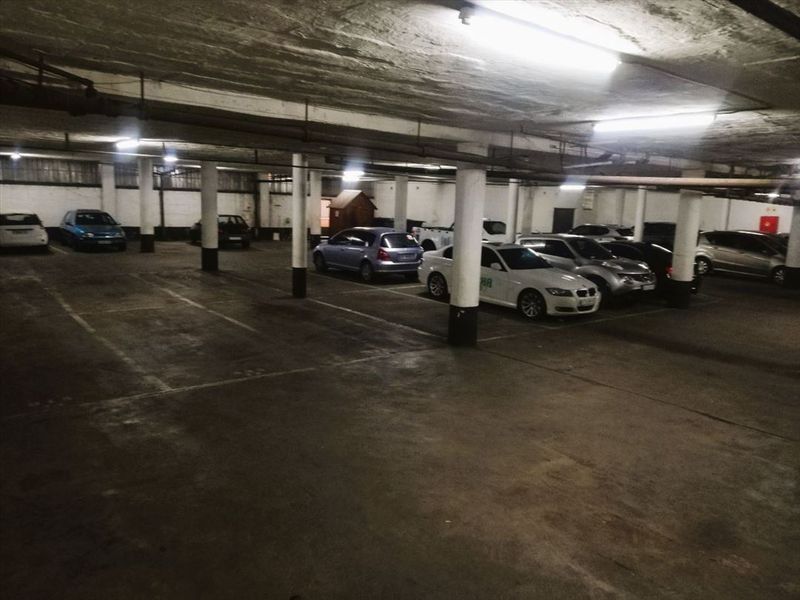 A large underground parking garage featuring concrete columns, fluorescent lighting, and marked parking bays.
