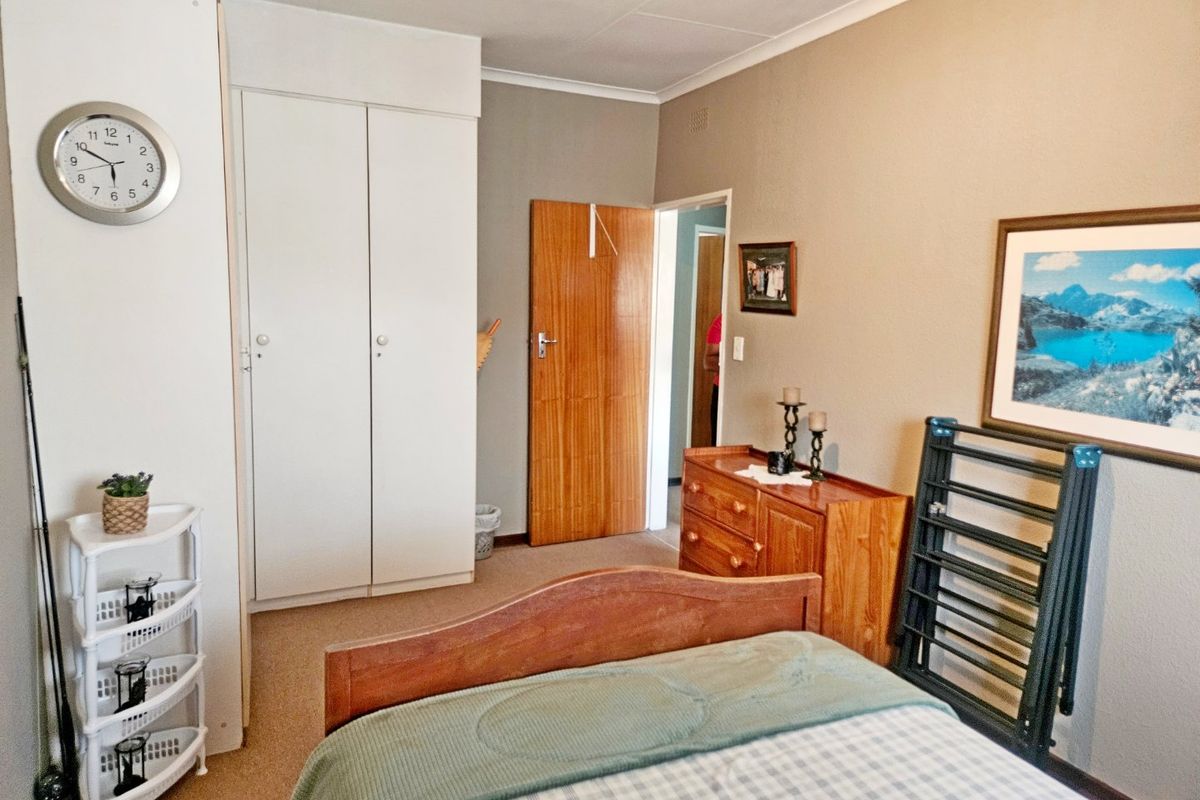 A functional bedroom featuring built-in cupboards, neutral wall tones, and carpeted flooring, providing a comfortable and practical living space.