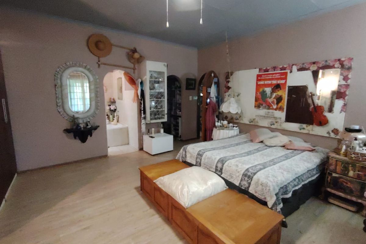 Spacious bedroom featuring laminate flooring, a ceiling fan, and an arched doorway leading to an adjoining bathroom area.