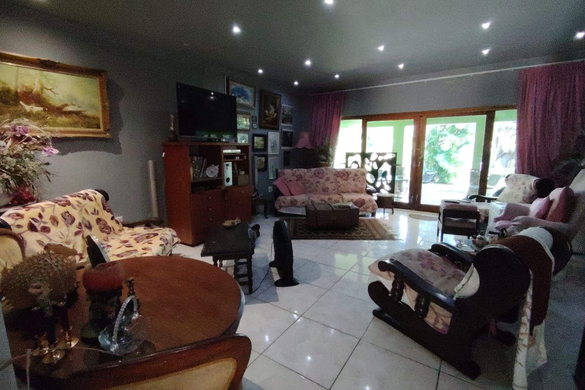 Spacious living room featuring large format floor tiles, recessed ceiling lighting, and sliding glass doors providing access to the outdoor area.