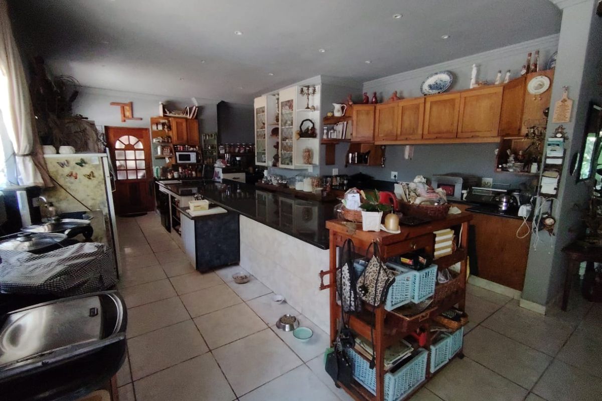 Spacious kitchen featuring extensive wooden cabinetry, granite countertops, and tiled flooring, offering a functional layout with ample storage and preparation space.
