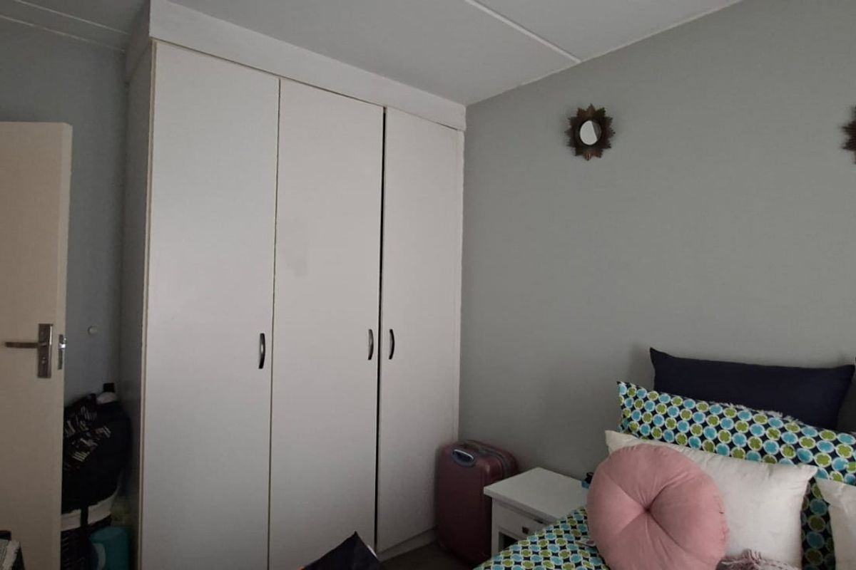 A bedroom featuring a white built-in wardrobe with ample storage space.