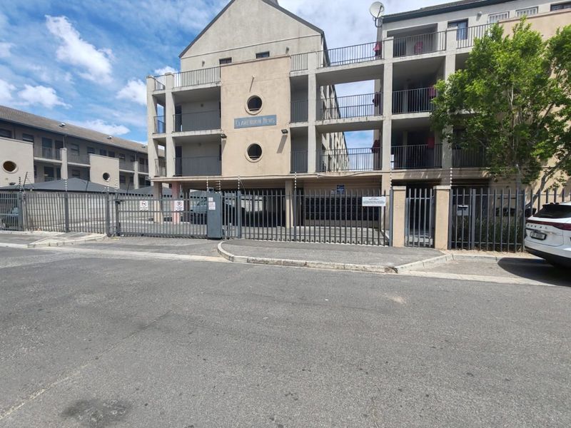 Front exterior view of Clarendon Mews apartment complex, featuring a secure gated entrance, electric fencing, and multi-level balconies.