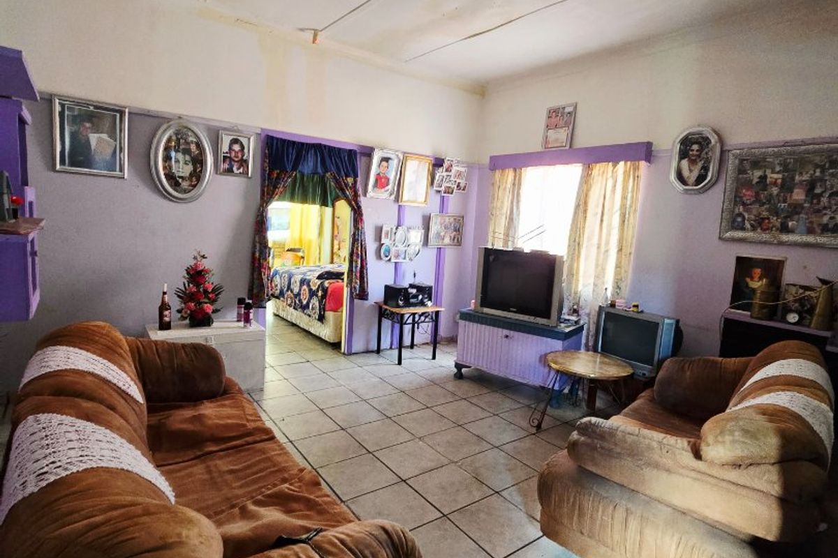 A living room featuring ceramic floor tiles and a traditional picture rail, currently requiring cosmetic updates and ceiling repairs.