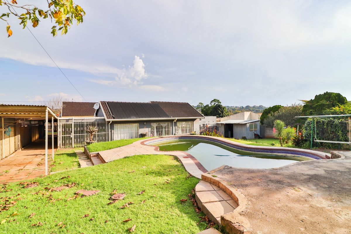 Rear view of the property featuring a swimming pool, lawn area, and a covered patio structure with solar panels on the roof.