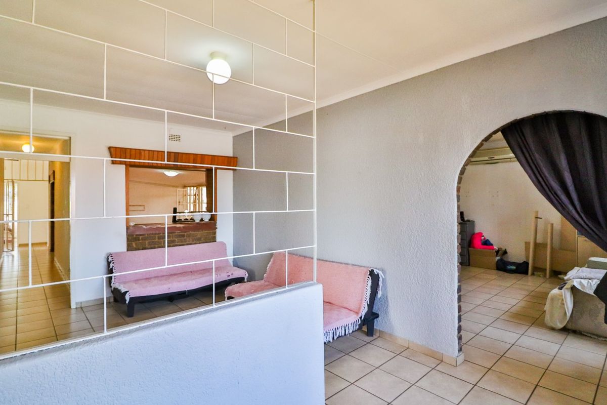 Living area featuring a decorative metal room divider, arched doorway, and tiled flooring, providing a functional layout with access to adjacent spaces.