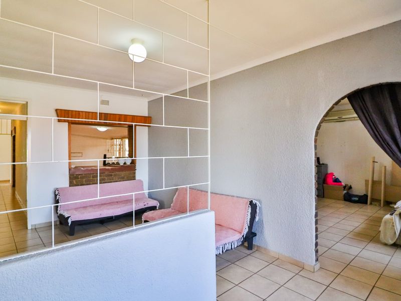 Living area featuring a decorative metal room divider, arched doorway, and tiled flooring, providing a functional layout with access to adjacent spaces.