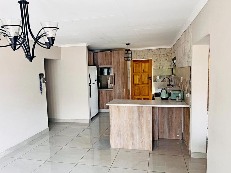 Open plan kitchen area featuring wood-look cabinetry, a central island, and tiled flooring, providing a functional space for cooking and dining.