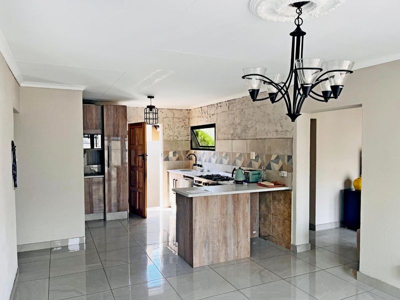 Kitchen area featuring wood-look cabinetry, gas hob, and tiled flooring. The space requires finishing touches to the wall surfaces and tiling.