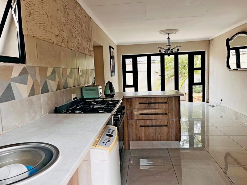 Open-plan kitchen and living area featuring modern cabinetry, gas hob, tiled flooring, and folding glass doors leading to the outdoor space.