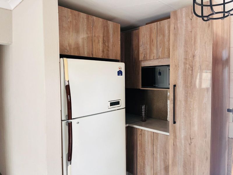 A compact kitchen area featuring wood-look cabinetry, a built-in microwave, and integrated storage space.