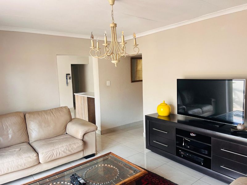 A living room featuring tiled flooring, a decorative chandelier, and coved ceiling details, providing a neutral base for interior design.