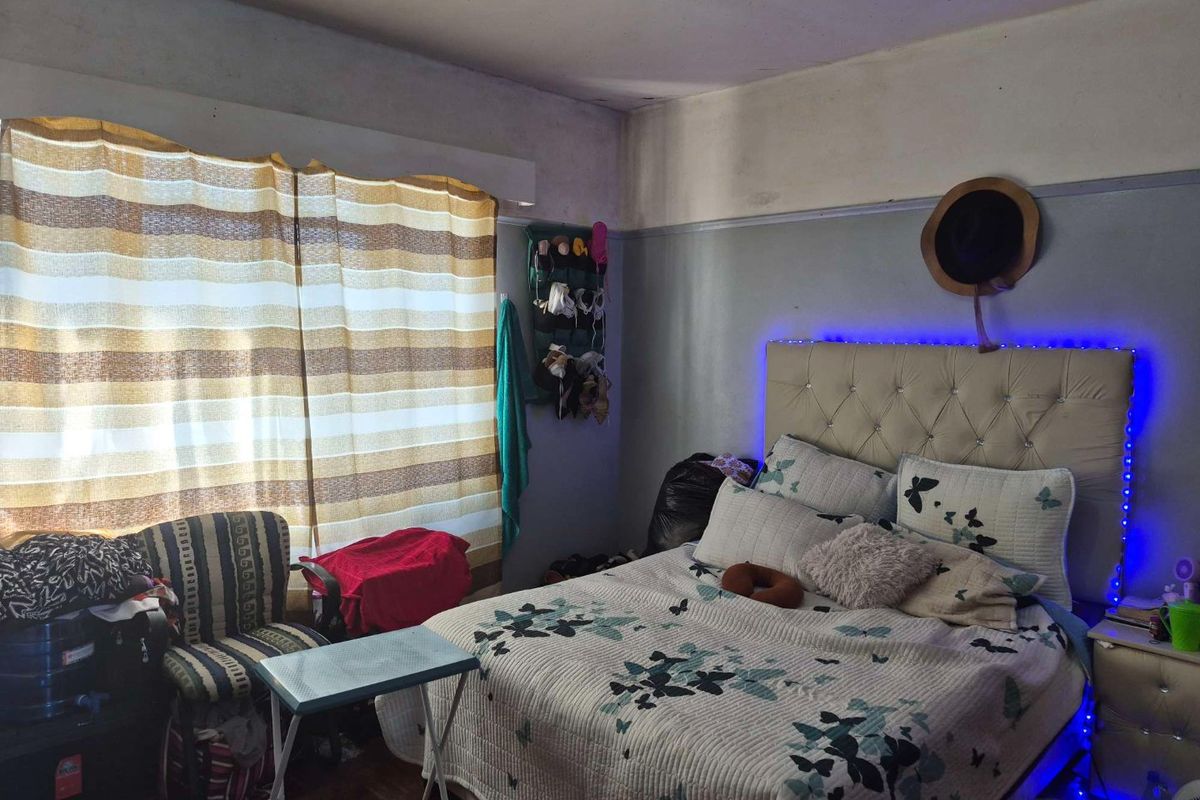 A bedroom featuring hardwood flooring and a classic picture rail, currently requiring maintenance to the ceiling and wall finishes.