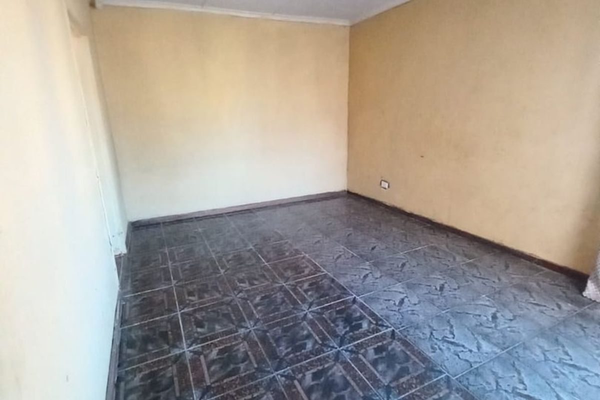 An empty bedroom featuring dark patterned floor tiles and a simple ceiling finish, providing a blank canvas for potential renovation or interior design updates.