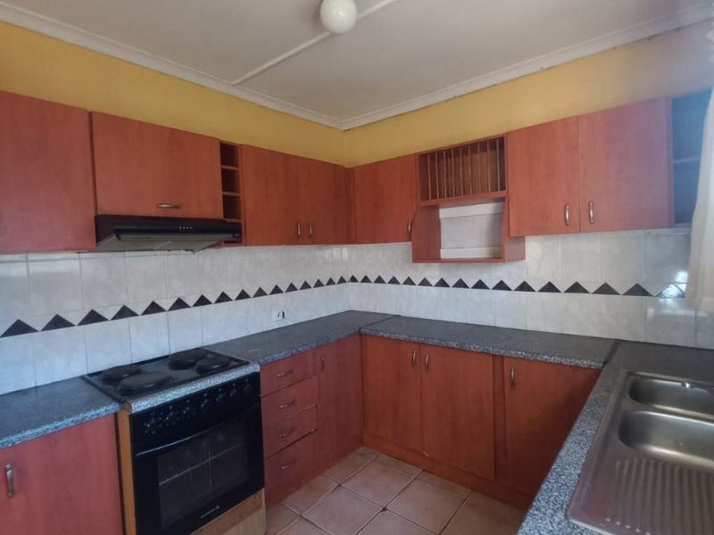 A functional kitchen featuring laminate cabinetry, granite-look countertops, a built-in oven with extractor fan, and a double bowl stainless steel sink.