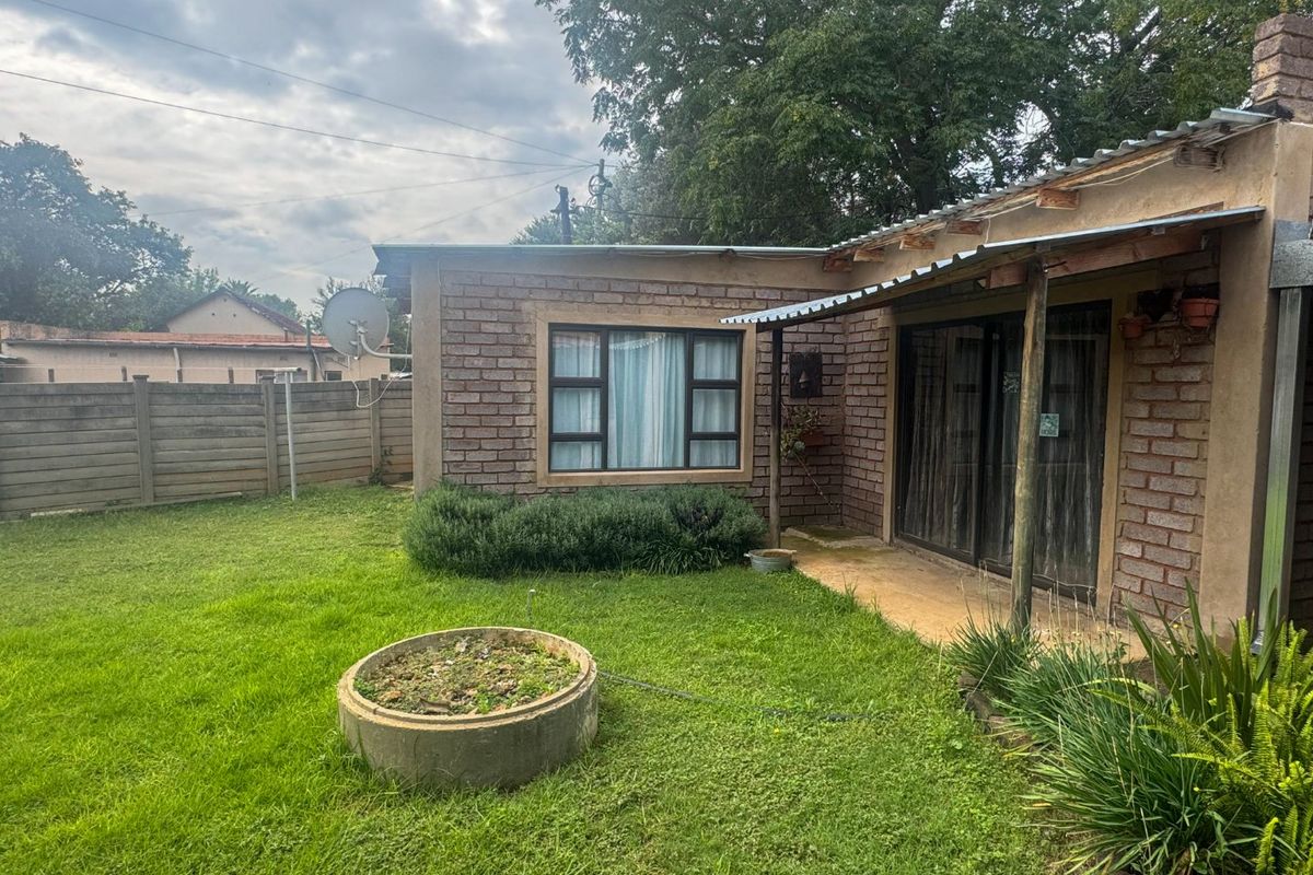 Rear view of the property featuring a brick facade, a small concrete patio area, and a private garden with a boundary wall.