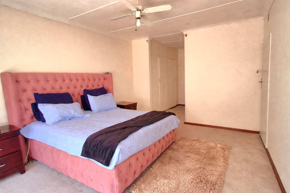 Spacious bedroom featuring built-in cupboards, a ceiling fan, and carpeted flooring, offering a blank canvas for potential updates and modernization.