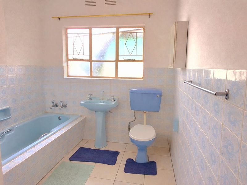 A dated bathroom featuring blue sanitaryware, tiled walls, and a tiled floor, offering potential for a modern renovation.