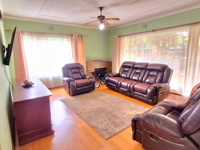 A spacious living room featuring laminate flooring, a ceiling fan, and a built-in fireplace, offering a comfortable and functional living space.