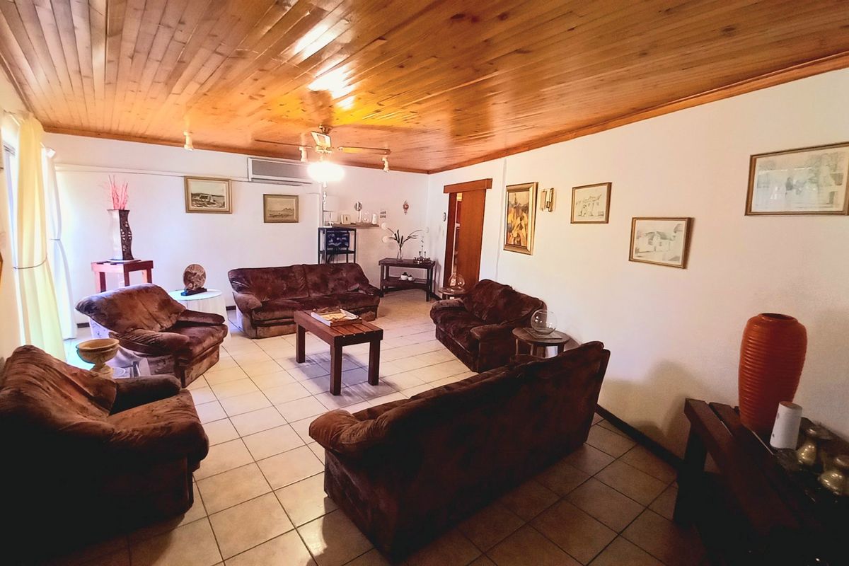 Spacious living room featuring a warm timber-clad ceiling, ceramic tiled flooring, and a wall-mounted air conditioning unit for climate control.