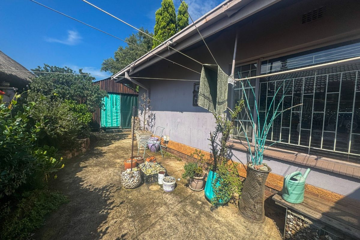 Rear exterior view of the house featuring a concrete paved area, security bars on windows, and a fixed washing line.