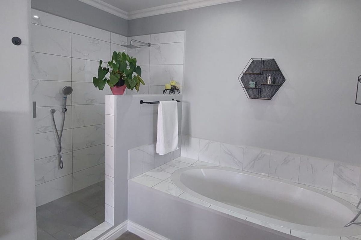 Modern bathroom featuring a walk-in shower with marble-look tiling and a separate built-in bathtub with a handheld shower attachment.