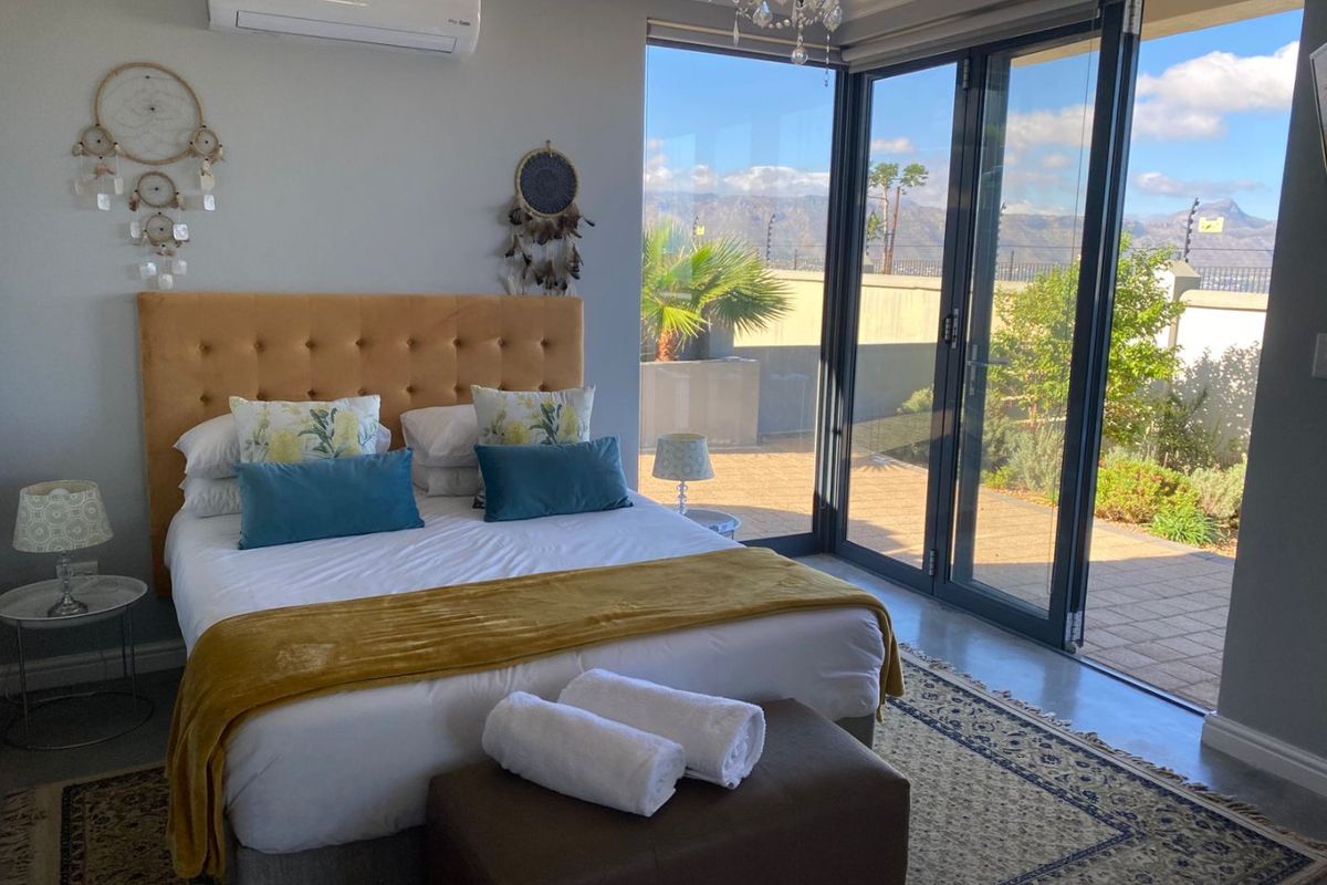 Modern bedroom featuring polished concrete floors, split-system air conditioning, and large glass sliding doors providing seamless access to the outdoor patio area.