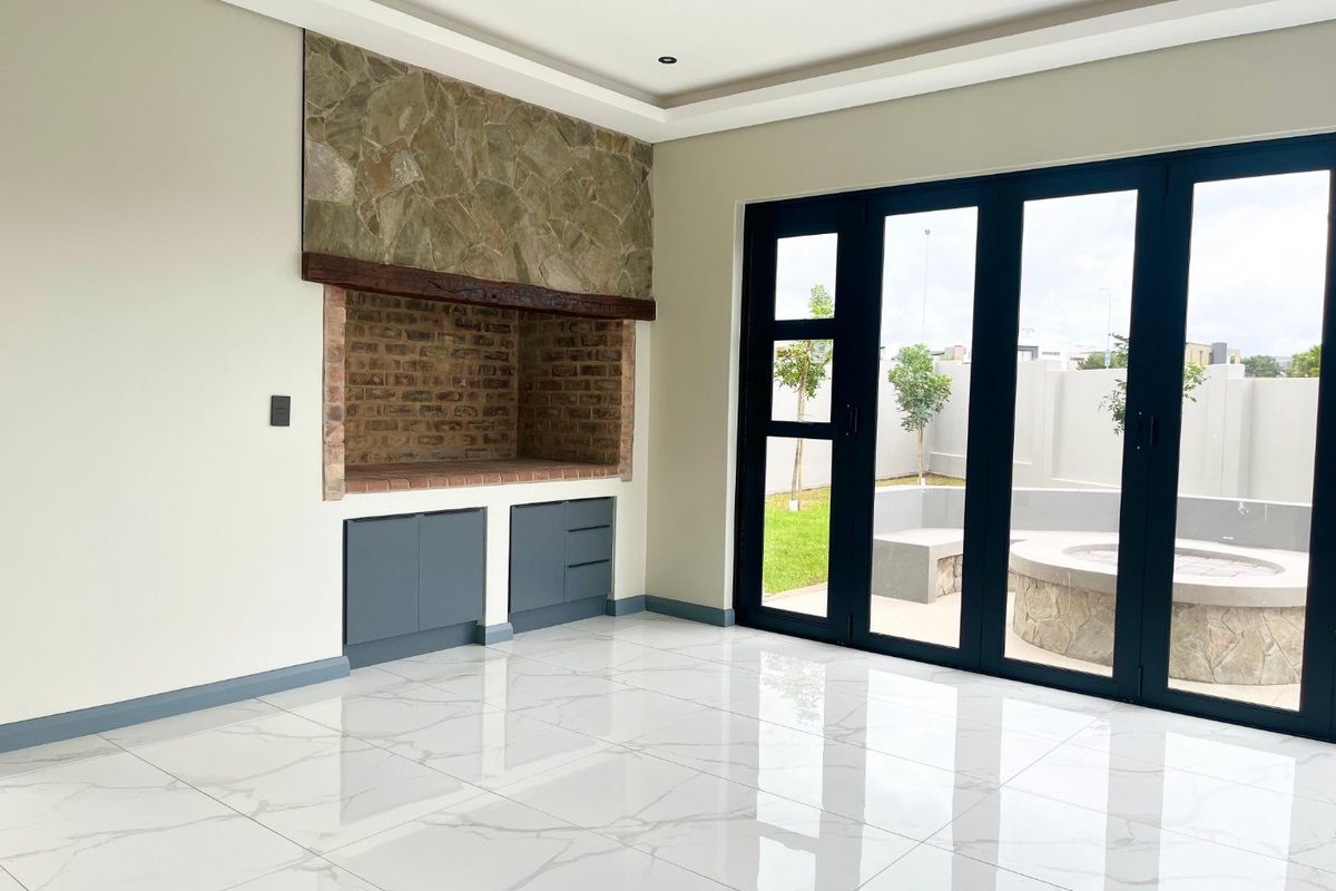 Spacious living area featuring a built-in fireplace with stone detailing, sleek porcelain flooring, and large bi-fold doors opening to the outdoor patio.