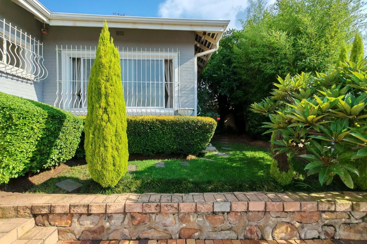 A well-maintained rear garden area featuring a brick retaining wall, paved walkway, and established landscaping adjacent to the house exterior.