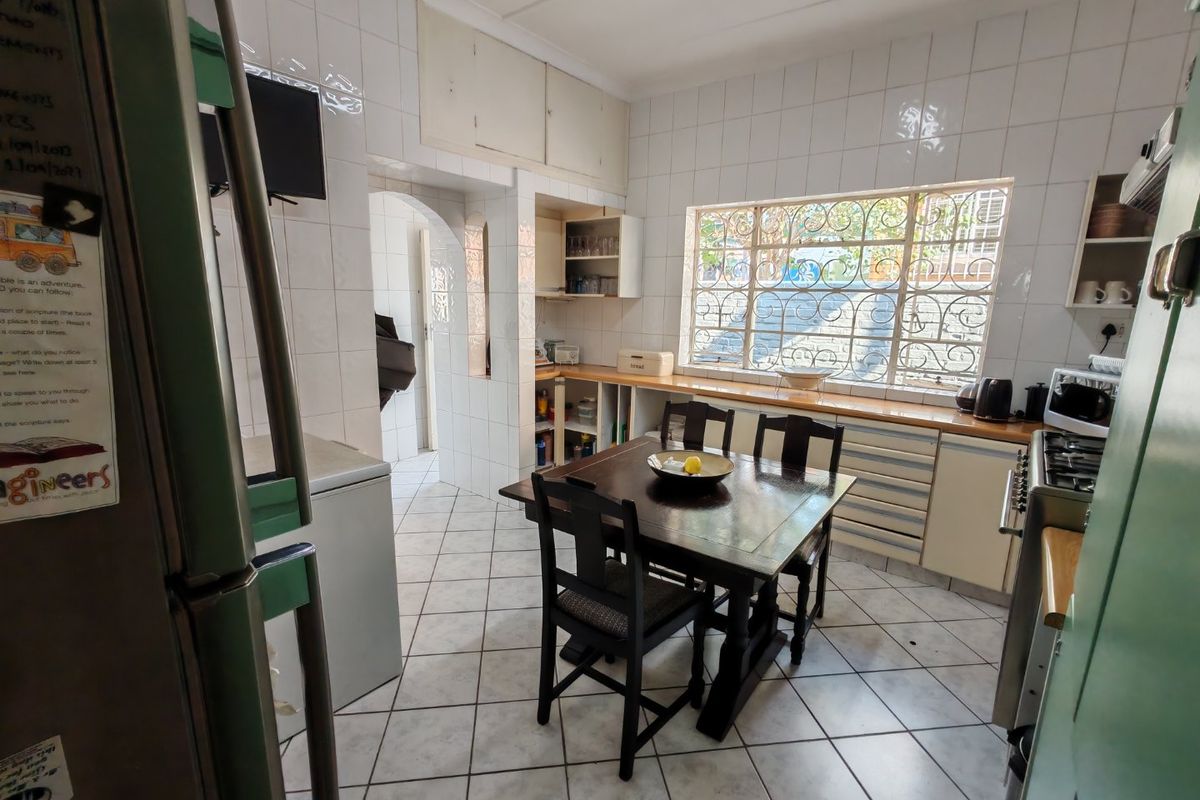 A functional kitchen featuring tiled walls and flooring, built-in cabinetry with wooden countertops, and a gas hob with an extractor fan.