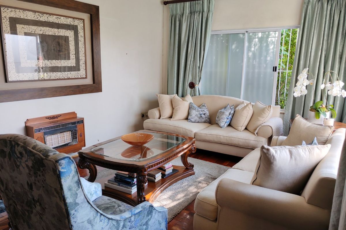 A comfortable living room featuring classic parquet flooring, a built-in gas fireplace, and large sliding glass doors that provide natural light.