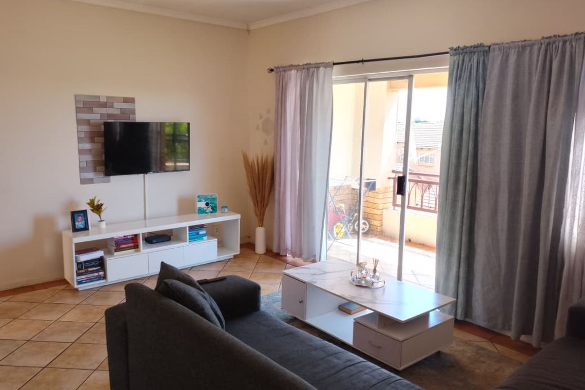 A comfortable living room featuring tiled flooring and a sliding glass door that provides access to an outdoor balcony area.