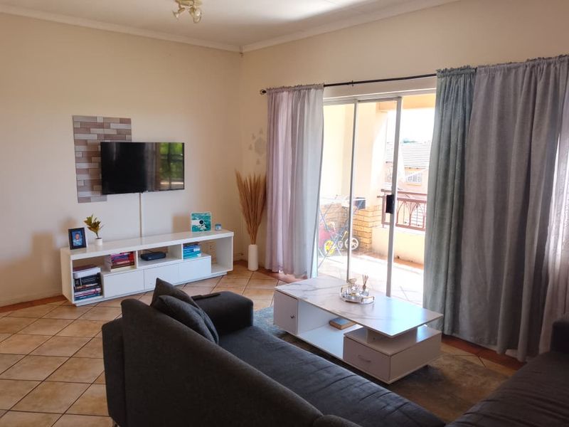 A comfortable living room featuring tiled flooring and a sliding glass door that provides access to an outdoor balcony area.