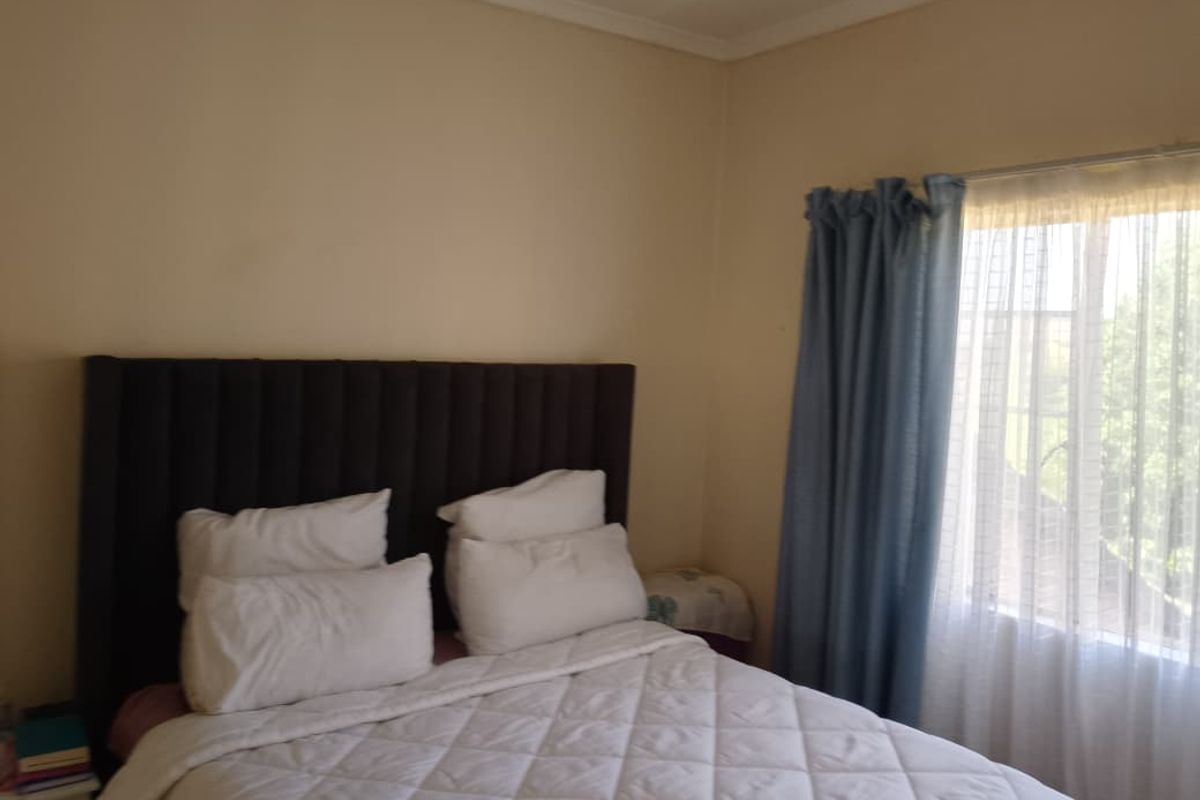 A standard bedroom featuring neutral wall finishes and a window with curtain treatments.