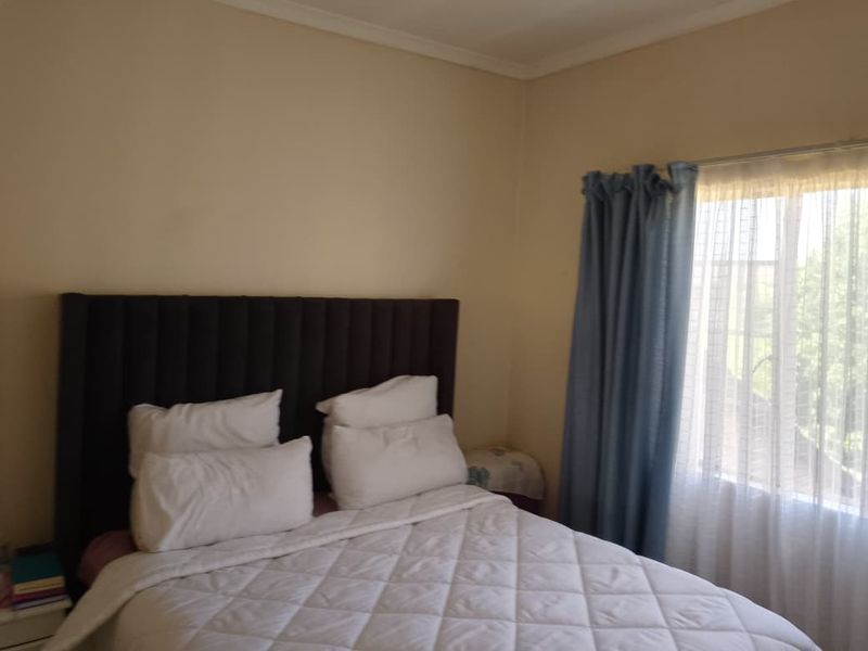 A standard bedroom featuring neutral wall finishes and a window with curtain treatments.