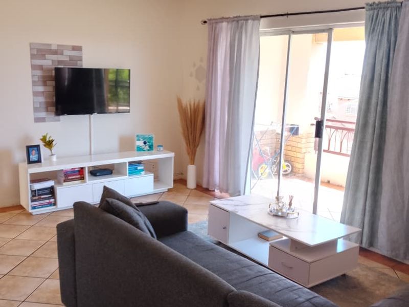 A living room featuring ceramic floor tiles and a sliding glass door providing access to an outdoor balcony area.