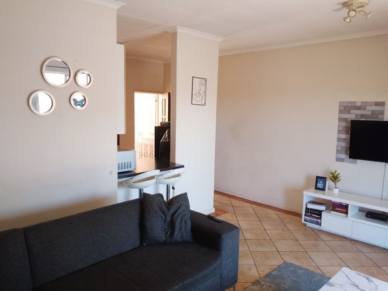 Open plan living area featuring tiled flooring and a breakfast bar connecting to the kitchen space.