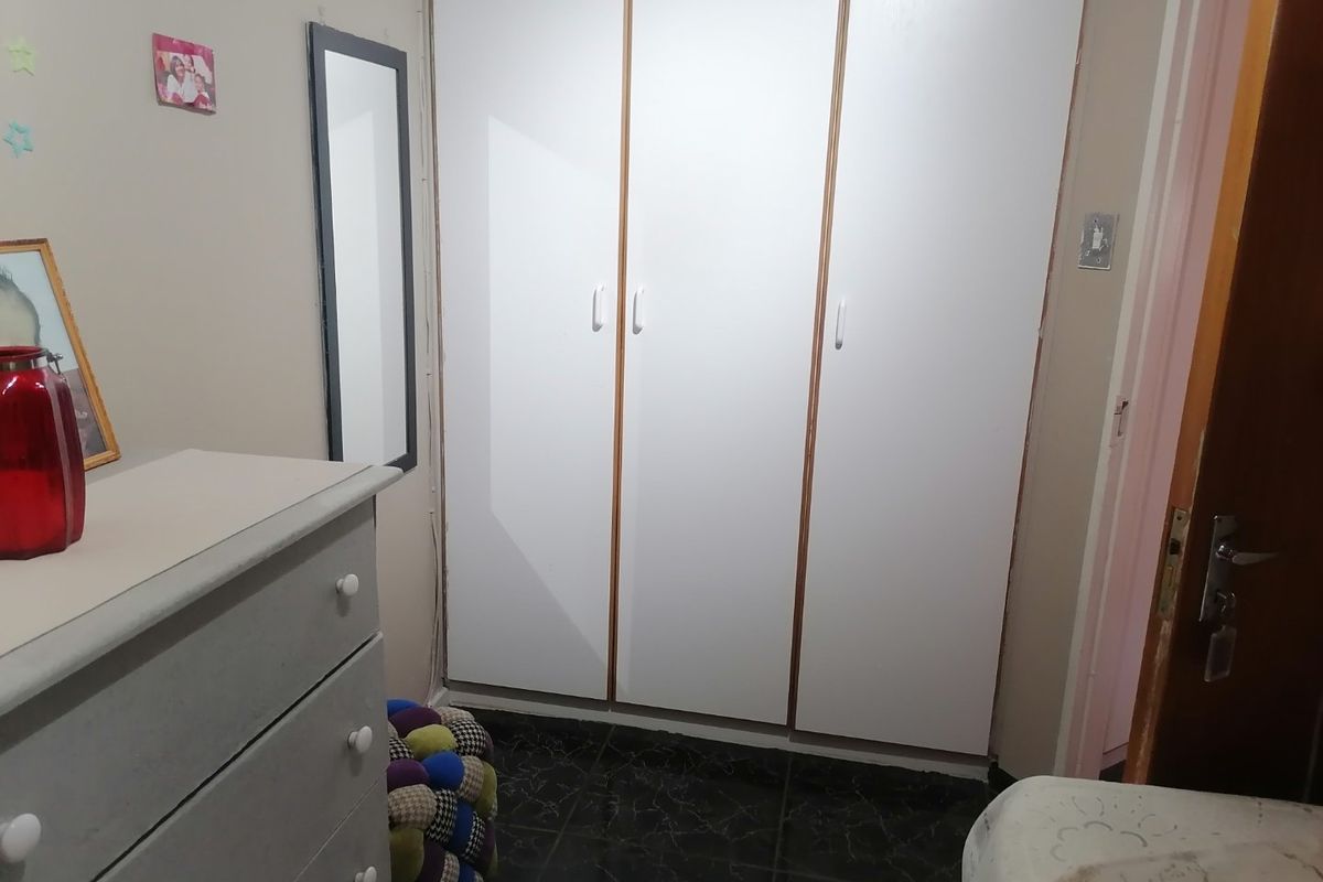 A bedroom featuring built-in white cabinetry and dark tiled flooring.