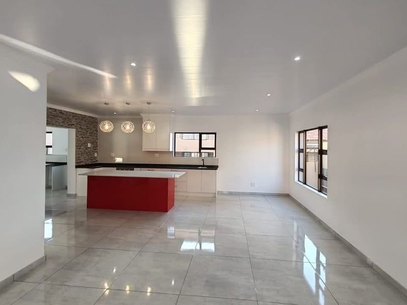 Spacious open-plan living and kitchen area featuring modern cabinetry, a central island, tiled flooring, and recessed lighting throughout.