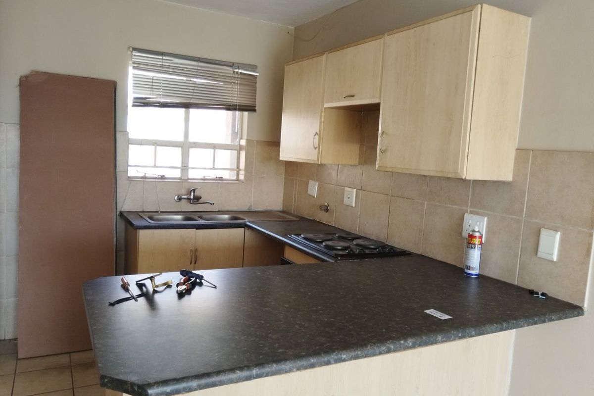 A functional kitchen featuring laminate cabinetry, a double bowl sink, and an integrated electric hob with tiled splashbacks.
