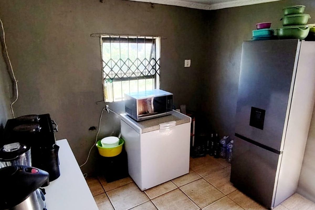 A functional kitchen area featuring tiled flooring, security window bars, and basic wall finishes, offering potential for renovation and modernization.