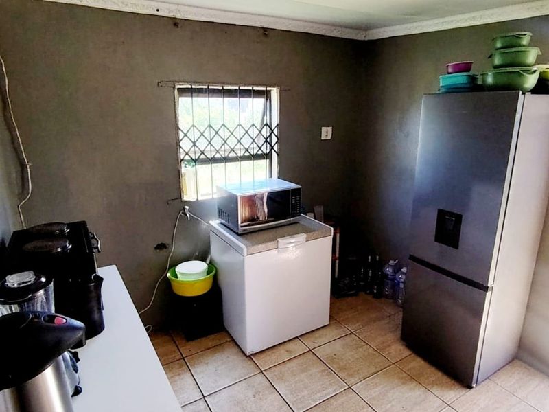 A functional kitchen area featuring tiled flooring, security window bars, and basic wall finishes, offering potential for renovation and modernization.