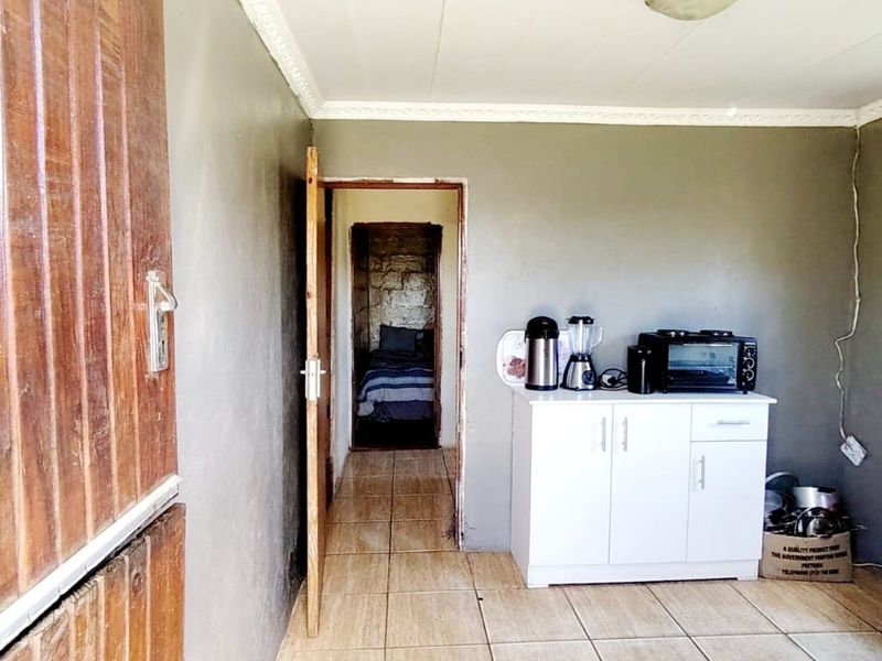 A functional hallway space featuring tiled flooring and access to an adjacent bedroom, showing basic finishes and exposed electrical wiring.