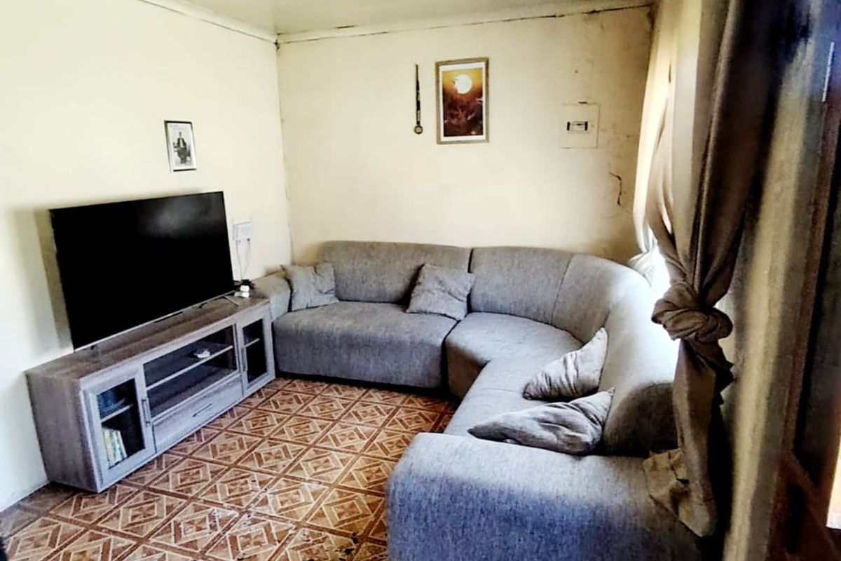 A living room featuring tiled flooring and cove cornicing, currently showing significant wear and tear on the walls and floor surfaces.