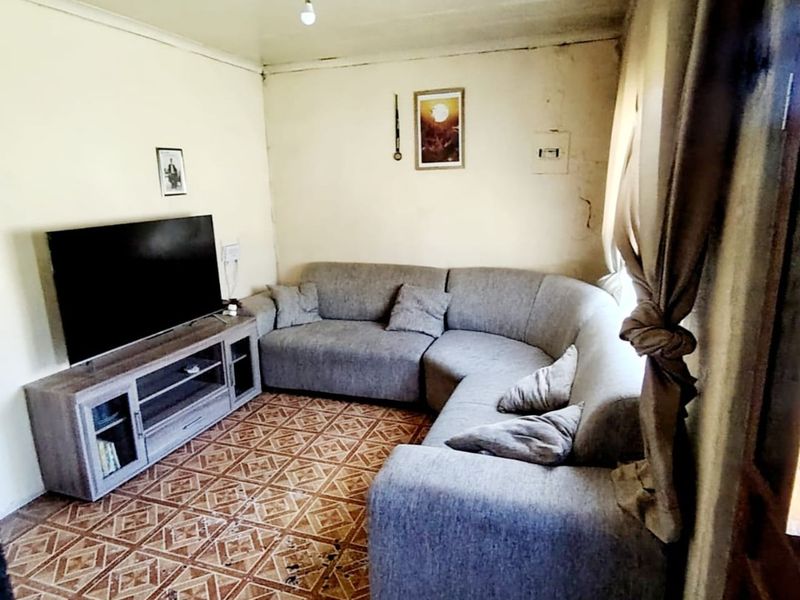A living room featuring tiled flooring and cove cornicing, currently showing significant wear and tear on the walls and floor surfaces.