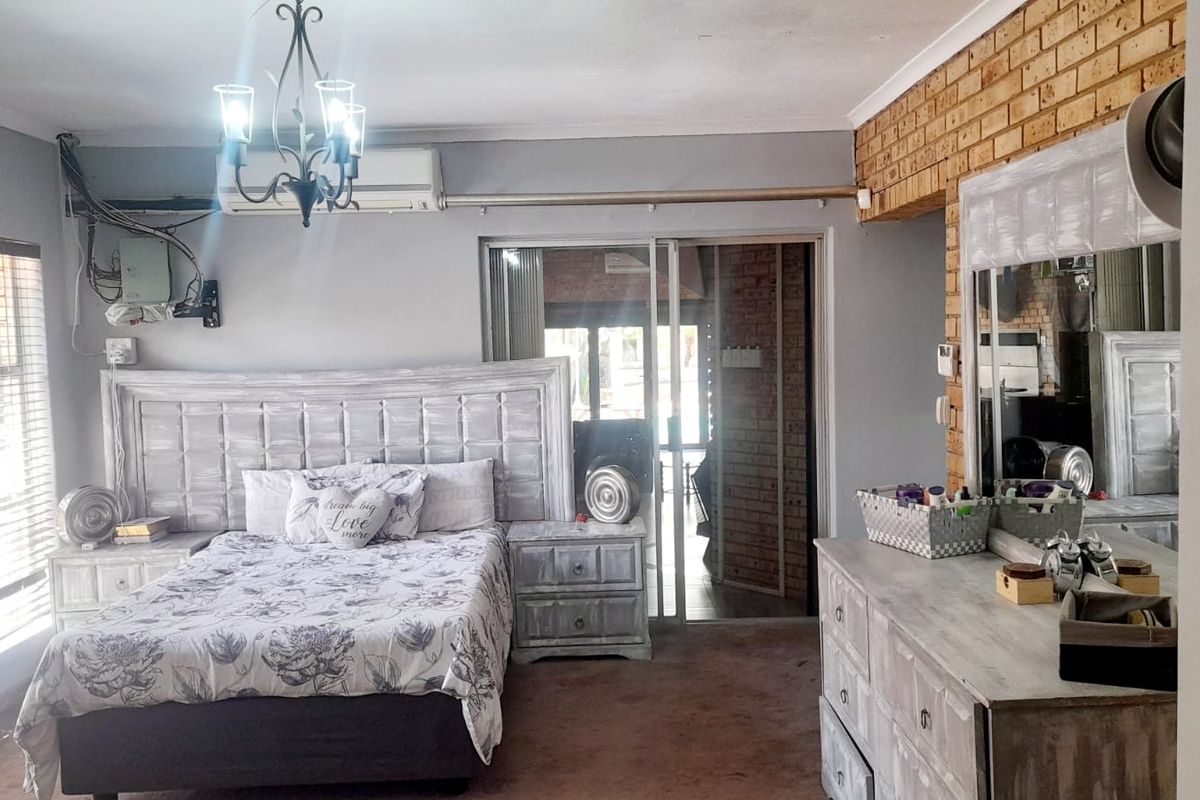 Spacious bedroom featuring an exposed brick accent wall, air conditioning unit, and sliding glass door access to an outdoor area.