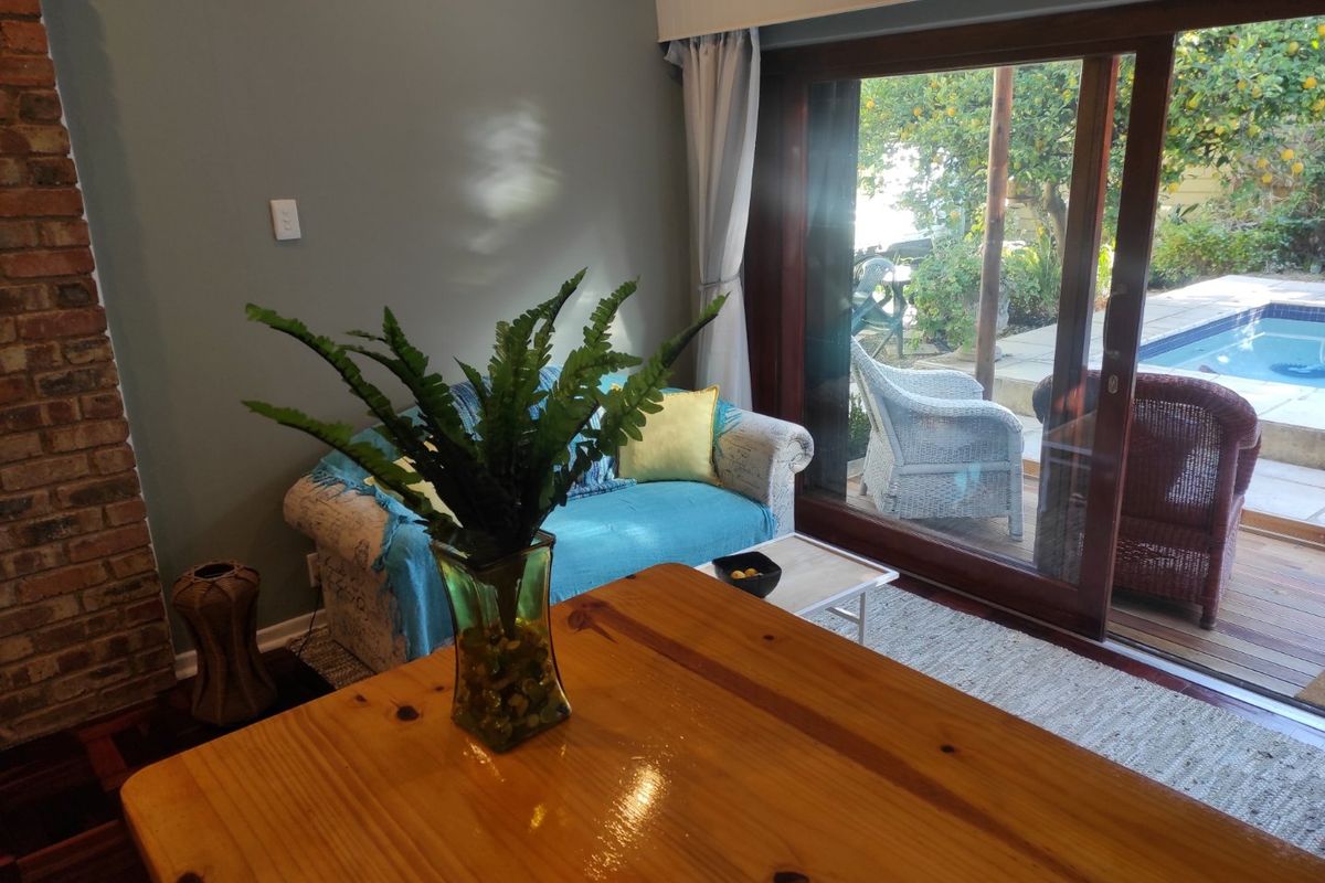 Living room featuring an exposed brick fireplace and large sliding glass doors providing direct access to the outdoor patio and pool area.