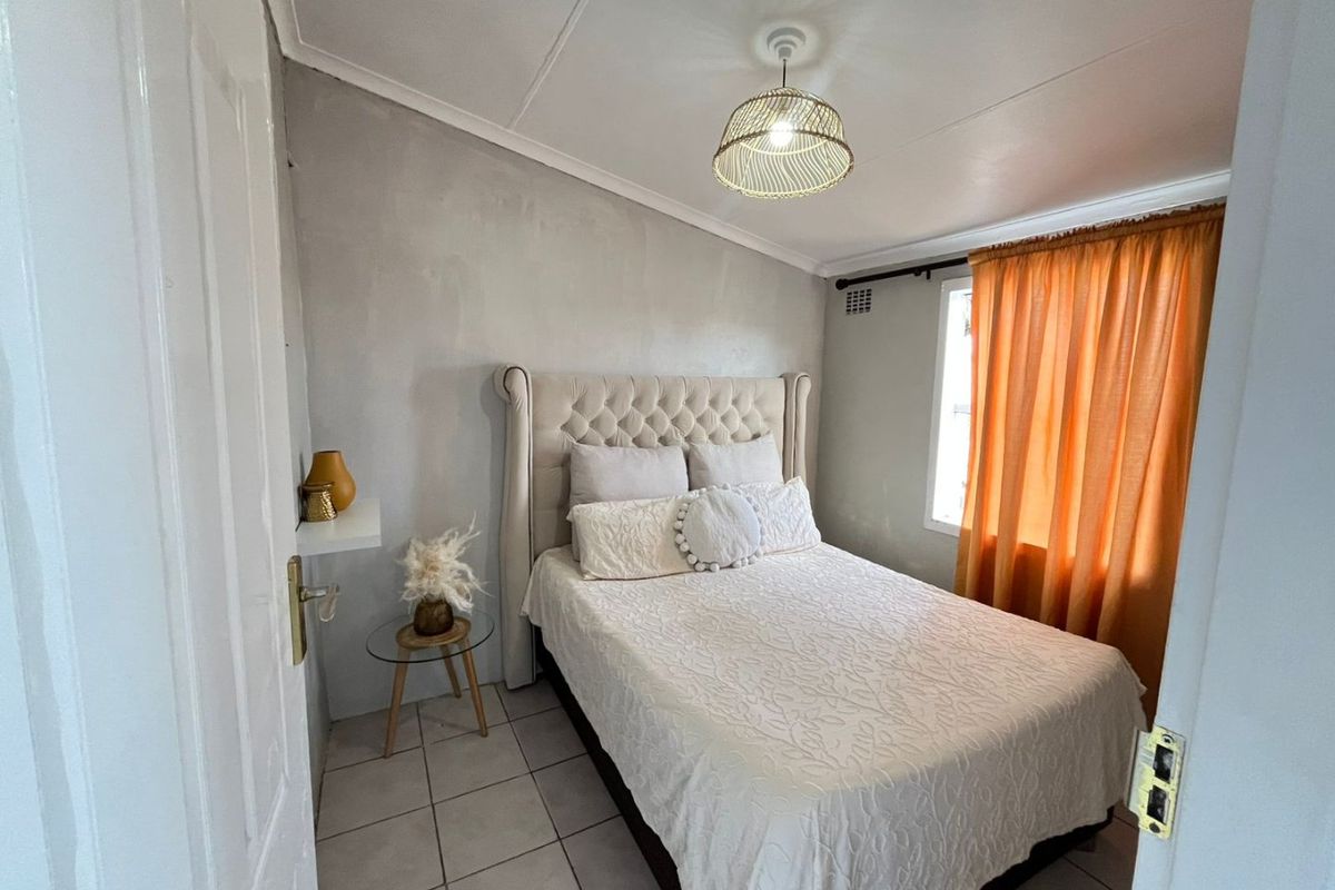A compact bedroom featuring tiled flooring, a neutral wall finish, and a window with curtain treatments.
