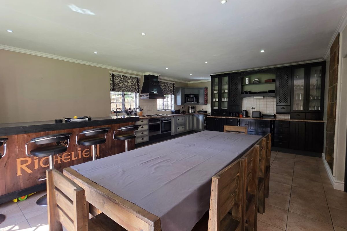 Spacious kitchen featuring dark cabinetry, a large central island with breakfast bar seating, and integrated appliances, offering a functional layout for cooking and dining.