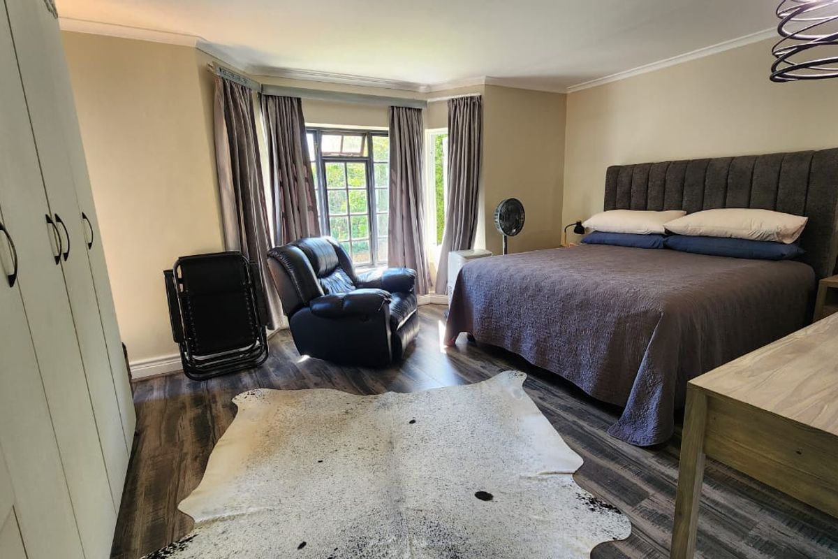 Spacious bedroom featuring laminate flooring, a large bay window, and built-in wardrobe storage.